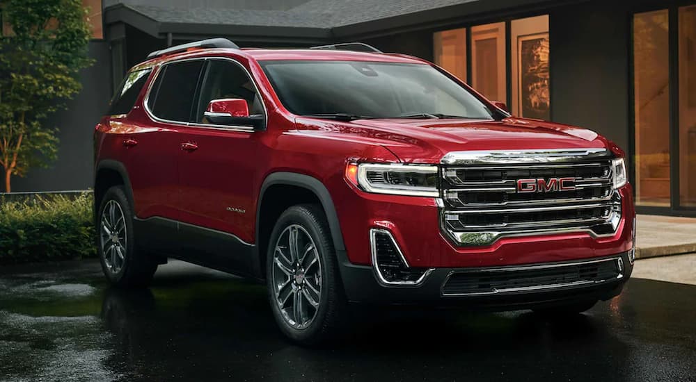 A red 2022 GMC Acadia is shown parked outside of a modern home.