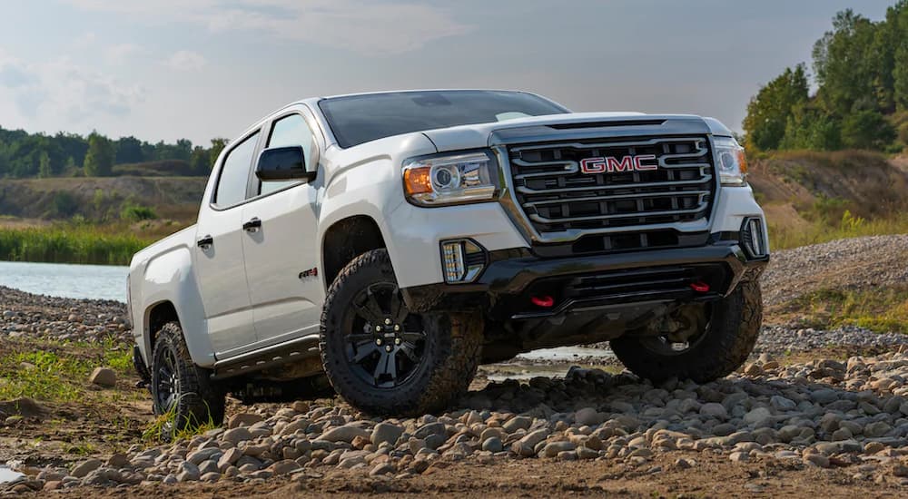 A white 2022 GMC Canyon AT4 is shown driving up a rocky road.