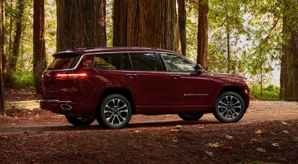 A red 2022 Grand Cherokee L Overland is shown from the side parked in a woodsy area.