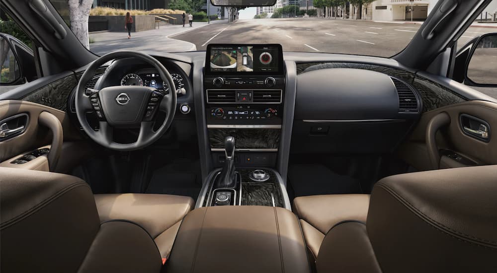 The black and brown interior of a 2022 Nissan Armada shows the steering wheel and infotainment screen.
