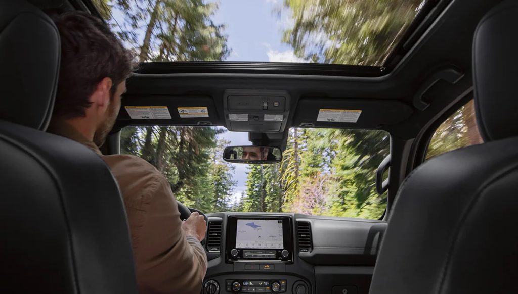 A man is shown driving a 2022 Nissan Frontier.