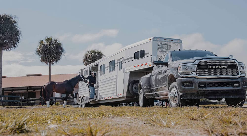 A silver 2022 Ram 3500 is shown towing a horse trailer.