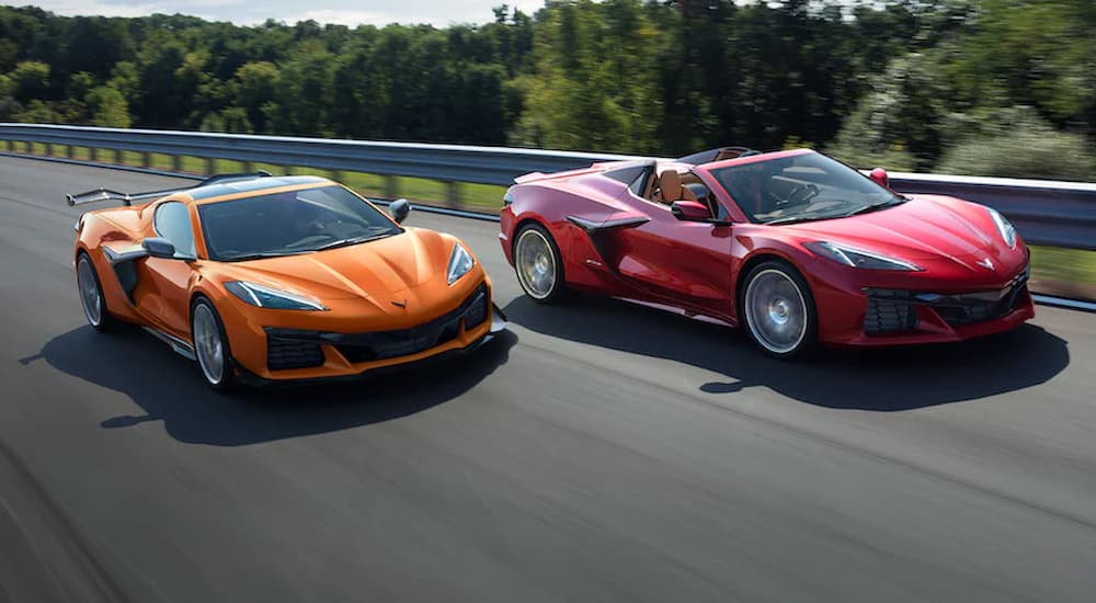 A red and an orange 2023 Chevy Z06 are shown driving on a highway.