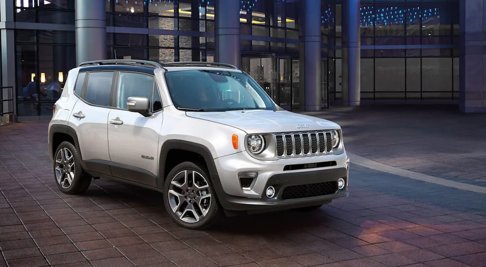 A silver 2021 Jeep Renegade is shown parked outside of a glass building.