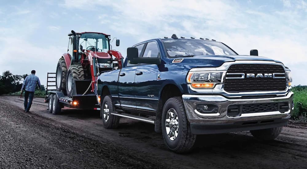 A blue 2022 Ram 2500 is shown towing a red tractor.