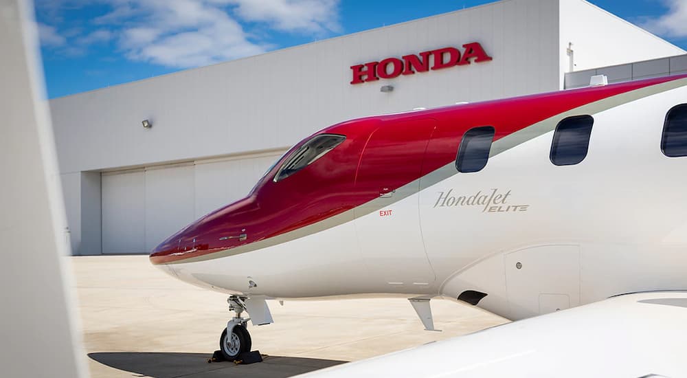 A white and red Honda Jet plane is shown at an airport.