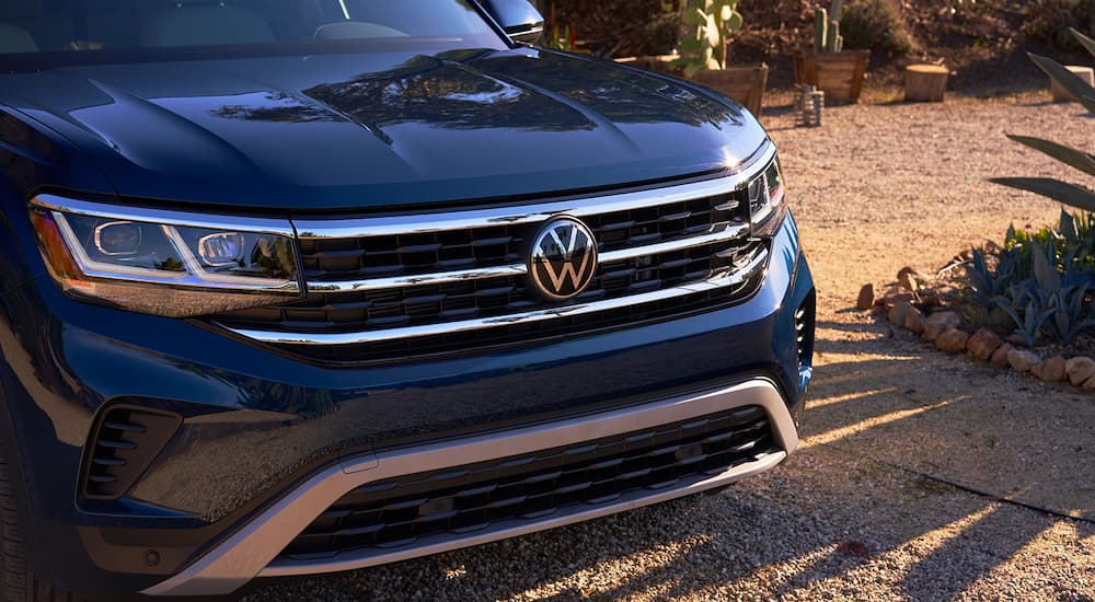 A close up shows the grille of a blue 2022 Volkswagen Atlas after searching 'Volkswagen dealer near me.'