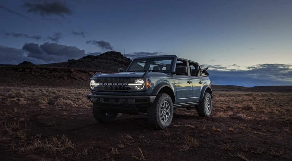 A blue 2021 Ford Bronco is shown from the side parked in the desert at sunset.