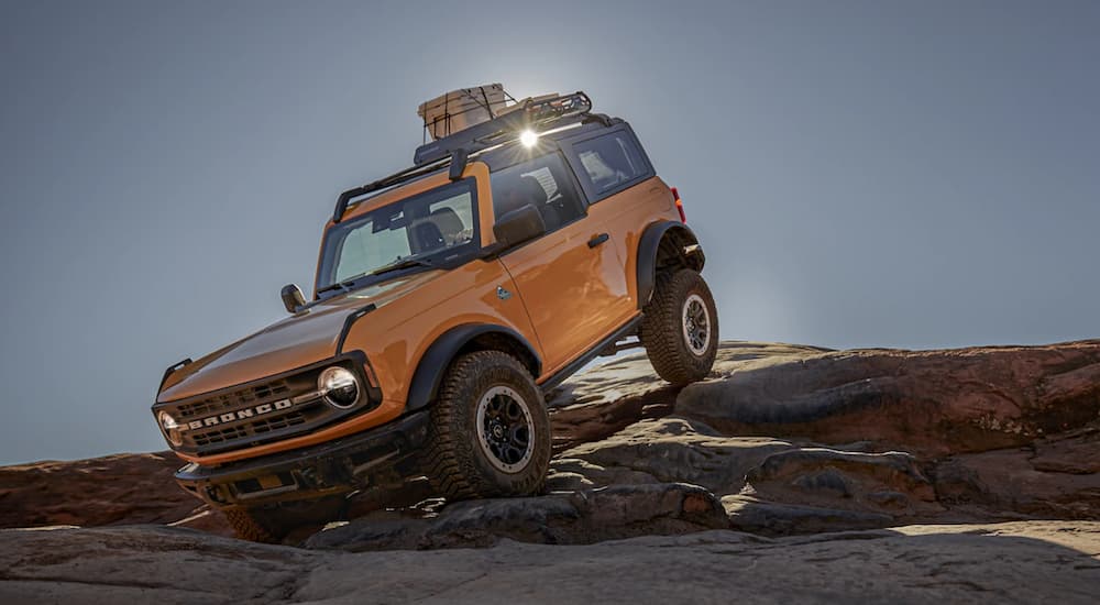 A yellow 2021 Ford Bronco is shown off-roading in the rocky desert.