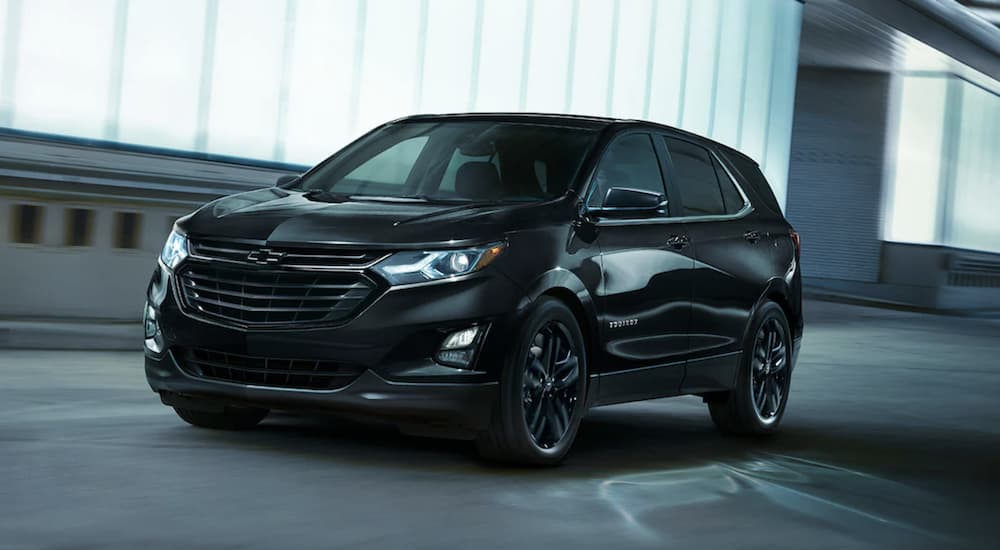 A black 2021 Chevy Equinox is shown from the front driving in a parking garage.