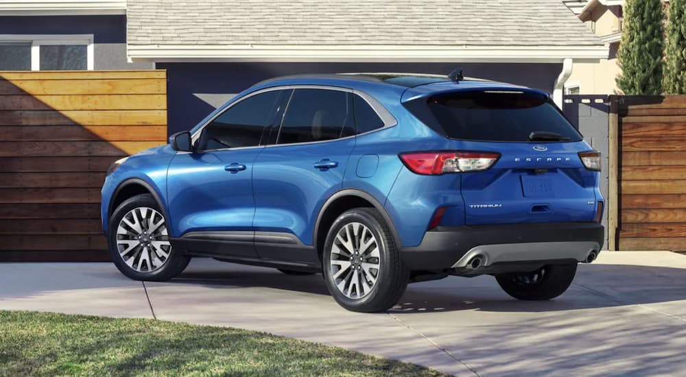 A blue 2021 Ford Escape is shown from the rear parked in a modern driveway after winning a 2021 Ford Escape vs 2021 Chevy Equinox comparison.