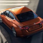 An orange 2021 Nissan Altima is shown from a high angle during a 2021 Nissan Altima vs 2021 Toyota Camry comparison.