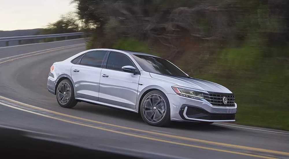 A silver 2021 Volkswagen Passat R-Line is shown from the side rounding a corner.