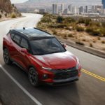 A red 2022 Chevy Blazer RS is shown driving away from a city.