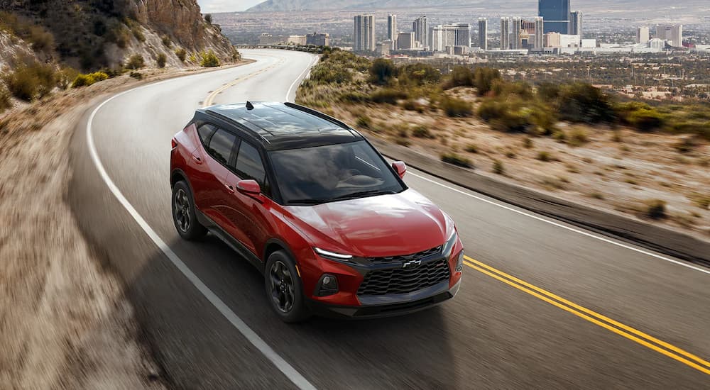 A red 2022 Chevy Blazer RS is shown driving away from a city.