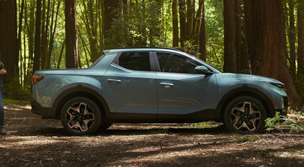 A blue 2022 Hyundai Santa Cruz is shown from the side parked in the woods.