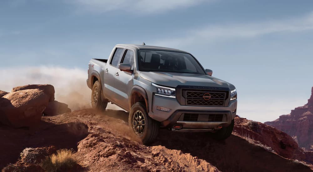 A silver 2022 Nissan Frontier is shown from the front off-roading in the desert.