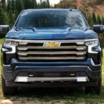A blue 2022 Chevy Silverado 1500 High Country is shown from the front parked in a grassy field.