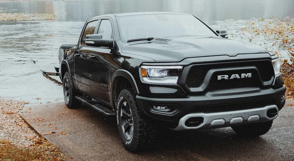 A black 2022 Ram 1500 is shown towing a boat trailer out of the water.