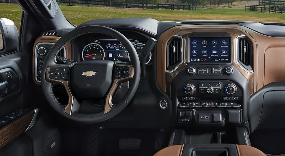 The black and brown interior of a 2022 Chevy Silverado 1500 shows the steering wheel and infotainment screen.