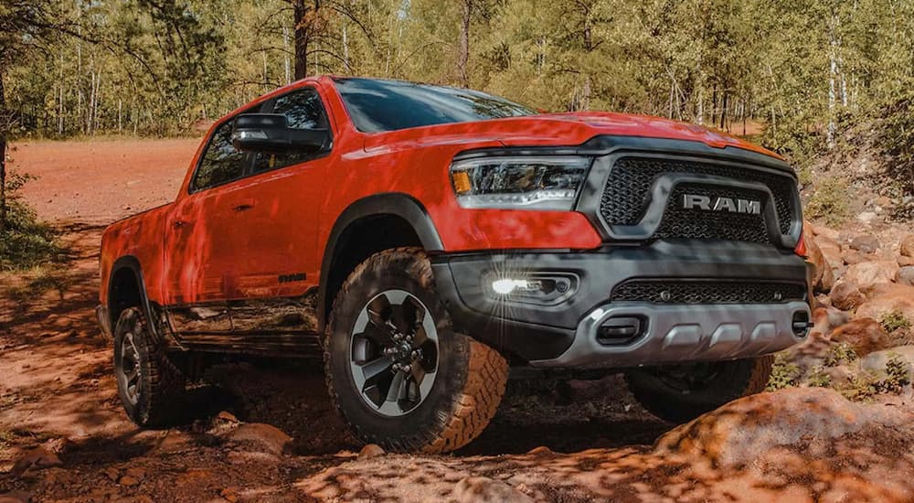 A red 2022 Ram 1500 is shown from the side parked on a rock in the forest.