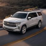 A white 2022 Chevy Suburban is shown from above driving on an open road.