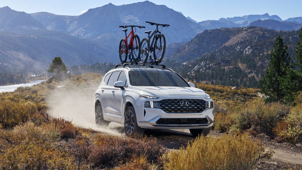 A white 2022 Hyundai Santa Fe is shown driving down a dusty remote trail.