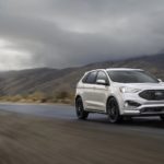 A white 2022 Ford Edge is shown driving on an empty road.