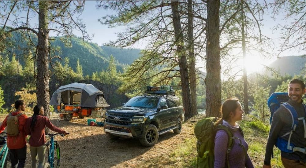 A green 2022 Ford Expedition Timberline is shown parked at a campsite during a 2022 Ford Expedition vs 2022 Toyota Sequoia comparison.