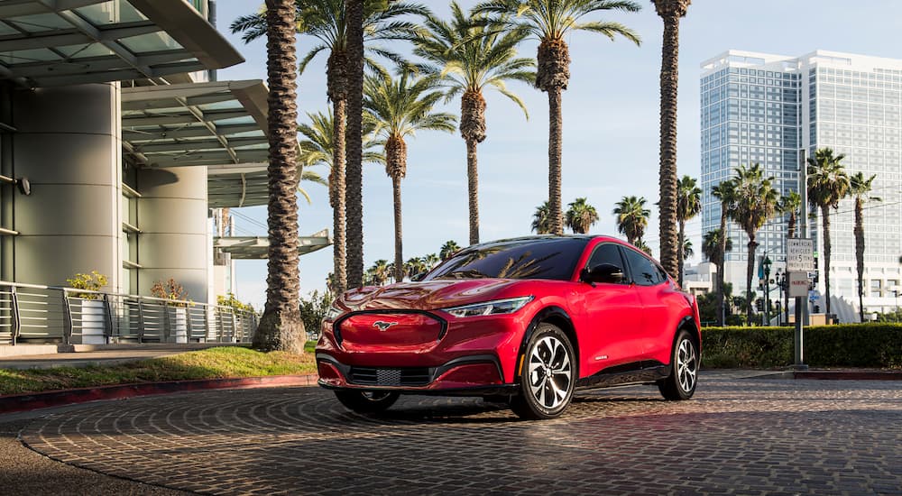 A red 2022 Ford Mustang Mach-E is shown parked outside of a modern building.