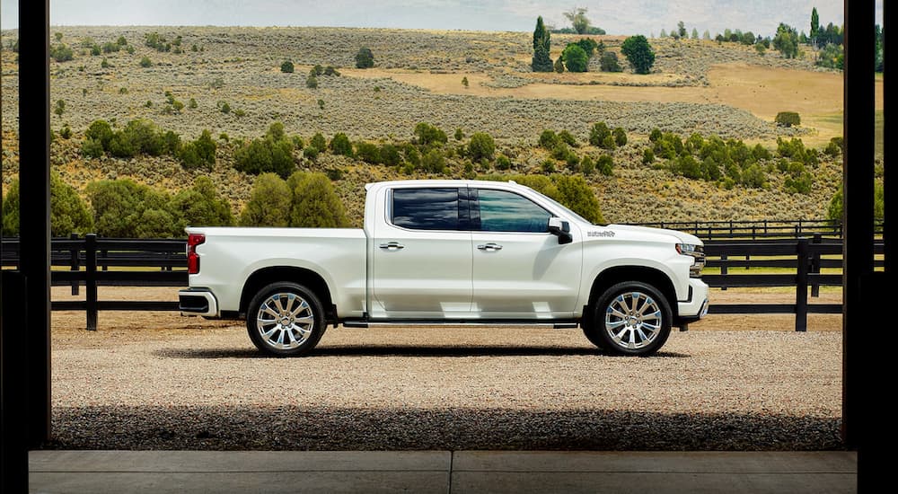 A white 2022 Chevy Silverado 1500 High Country is shown from the side parked on a farm.