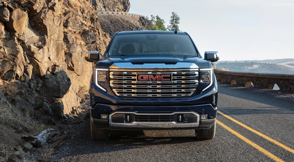 A blue 2022 GMC Sierra Denali is shown from the front driving during a 2022 GMC Sierra 1500 vs 2022 Chevy Silverado 1500 comparison.