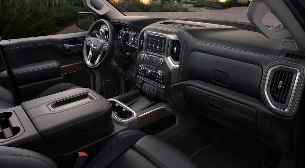 The black interior of a 2022 GMC Sierra Denali shows the center console and steering wheel.