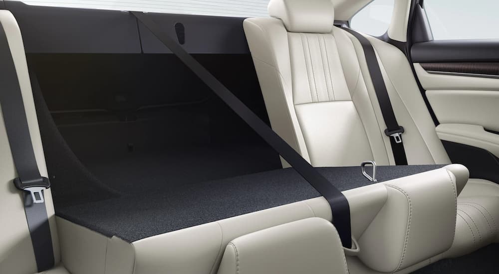 The white interior of a 2022 Honda Accord Hybrid 2.0T shows the back seat folded down.
