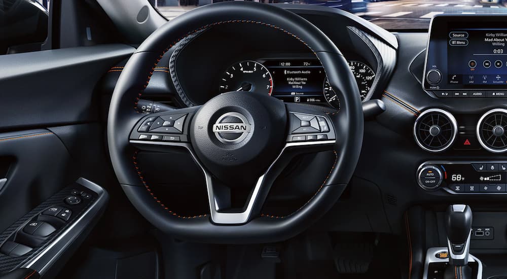 The black interior of a 2022 Nissan Sentra shows the steering wheel and infotainment screen.
