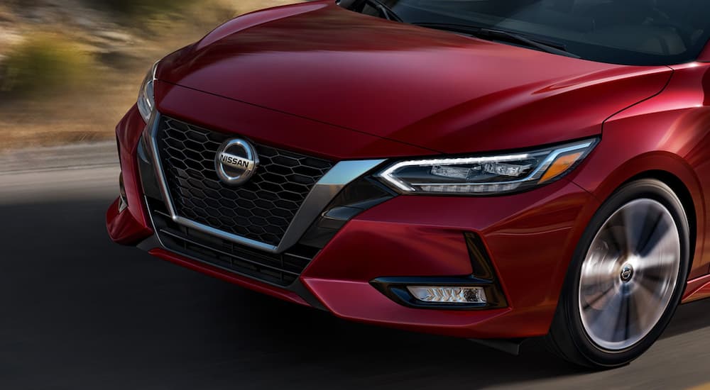 The front of a red 2022 Nissan Sentra is shown in close up driving on an open road.