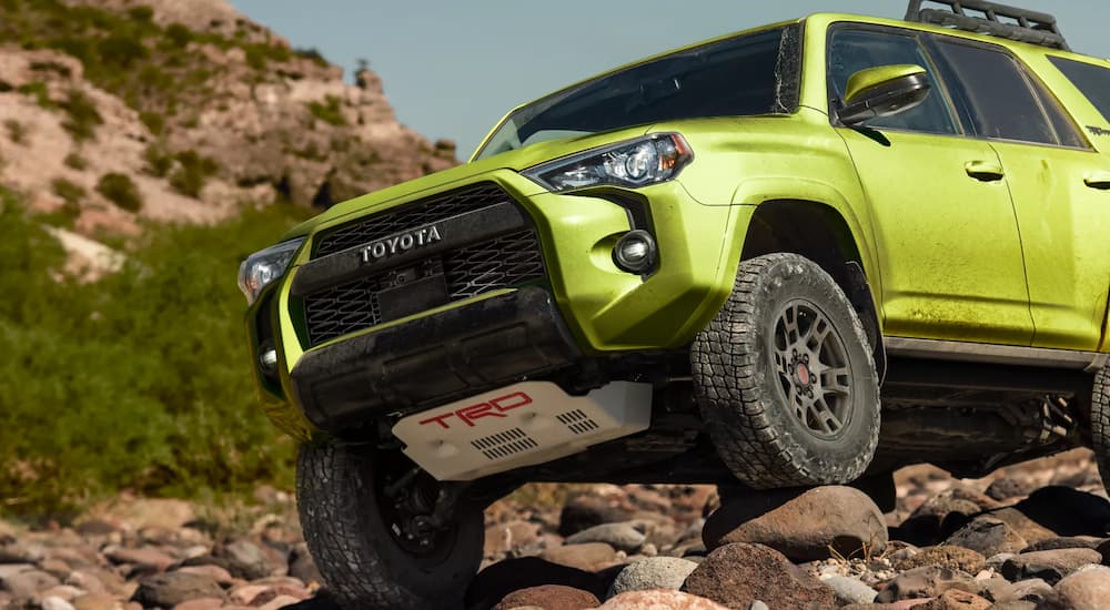A green 2022 Toyota 4Runner TRD Pro is shown off-roading on rocks.