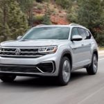 A silver 2022 Volkswagen Atlas SE is shown driving down an empty highway.