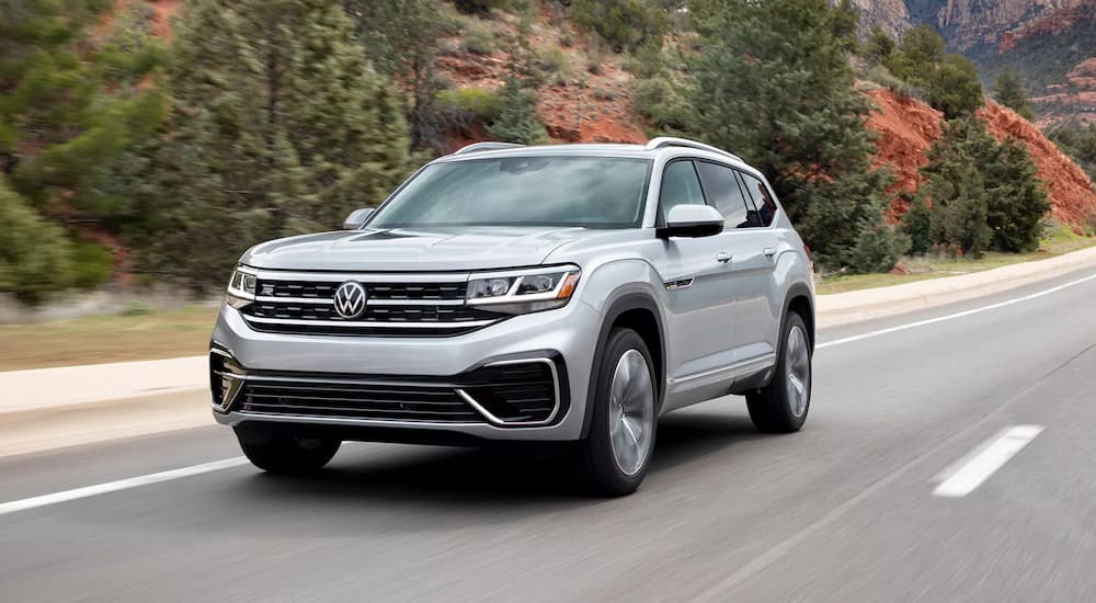 A silver 2022 Volkswagen Atlas SE is shown driving down an empty highway.