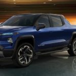 A blue 2024 Chevy Silverado EV is shown at a charging station.