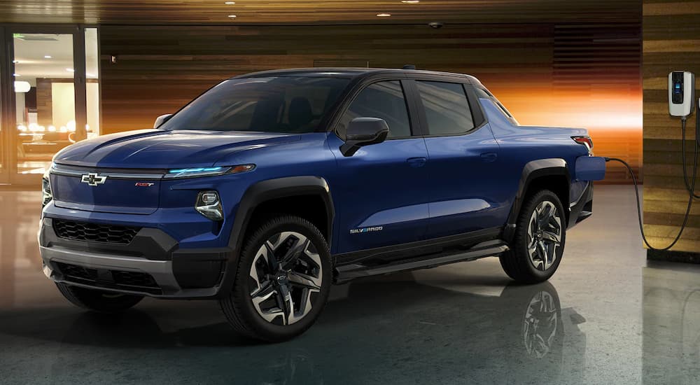 A blue 2024 Chevy Silverado EV is shown at a charging station.