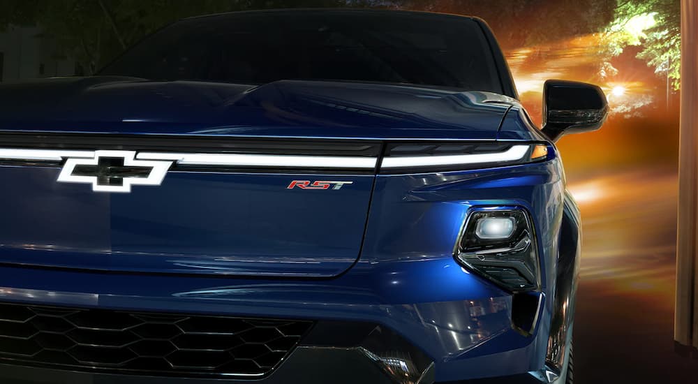 A close up shows the grille and badge on a blue 2024 Chevy Silverado EV.