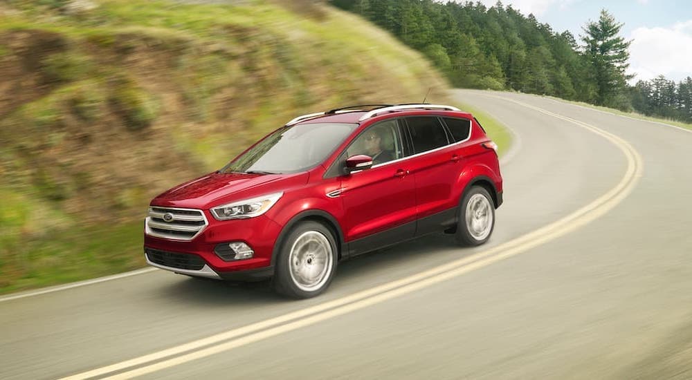 A red 2018 Ford Escape is shown from the side driving on an open road.
