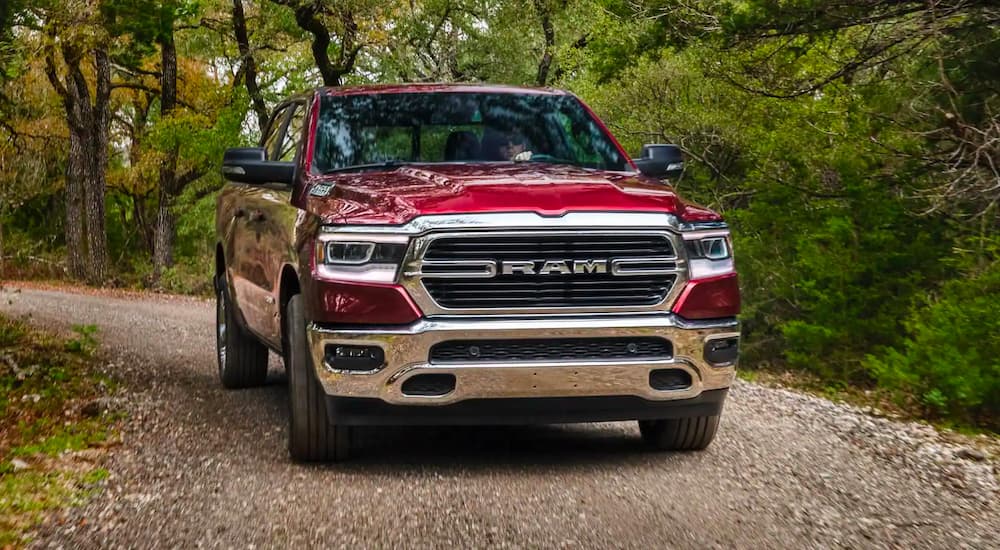 A red 2020 Ram 1500 is shown from the front driving on a woodland path.