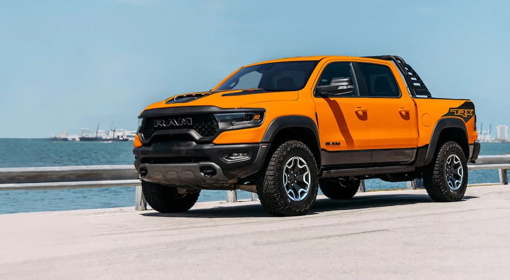 An orange 2021 Ram 1500 TRX Ignition Edition is shown parked next to the ocean.