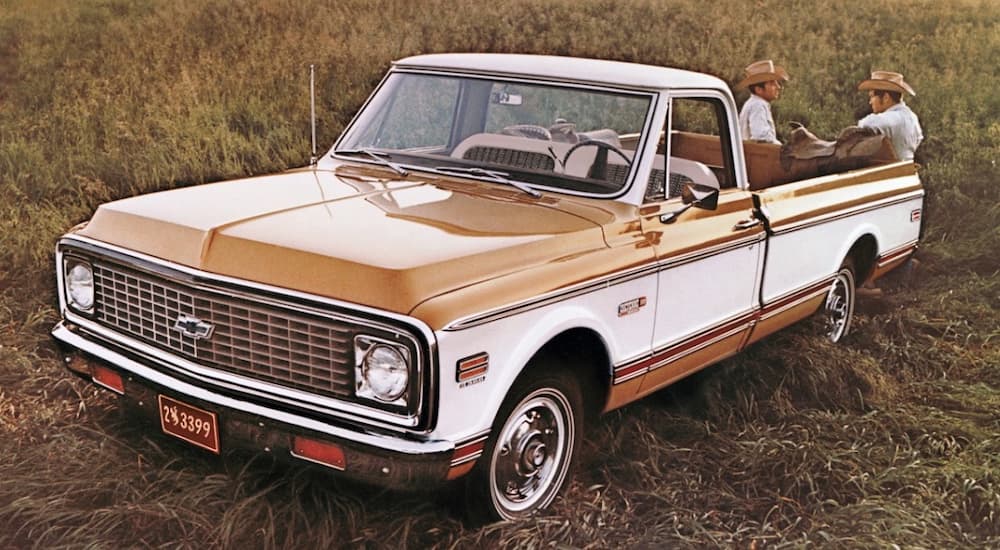 A brown and white 1971 Chevy Cheyenne is shown parked in a field.