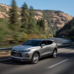 A silver 2022 Chevy Blazer Premier is shown driving on an empty mountain highway.