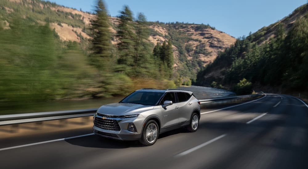 A silver 2022 Chevy Blazer Premier is shown driving on an empty mountain highway.