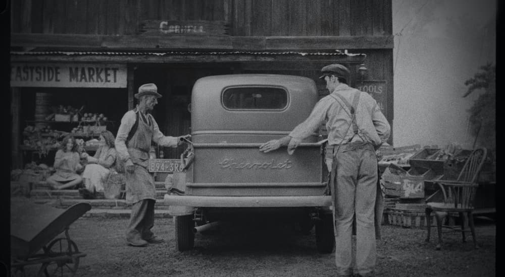 Two men are shown inspecting a vintage Chevy long before the days of Chevy pre-order.
