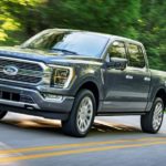 A grey 2021 Ford F-150 Limited is shown driving on an empty road after visiting a Ford F-150 dealer.